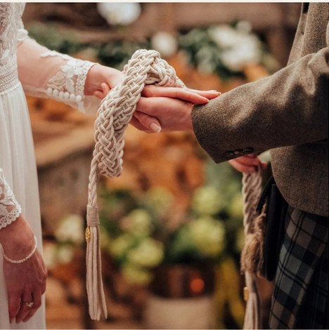 Handfasting cords tied around a couple's hands