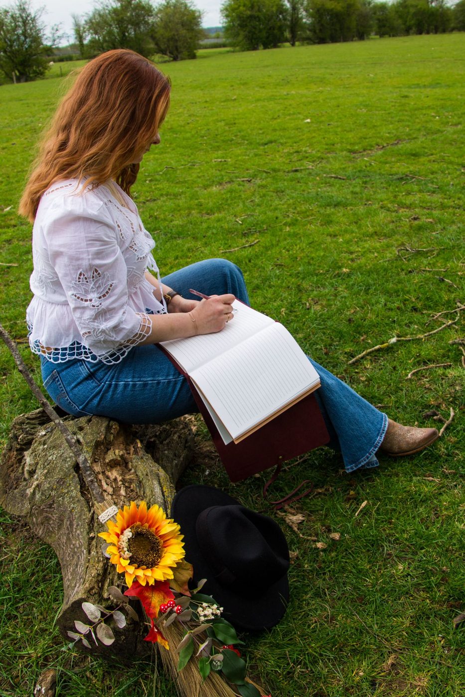 Hannah Collins writing in a journal on a fallen tree